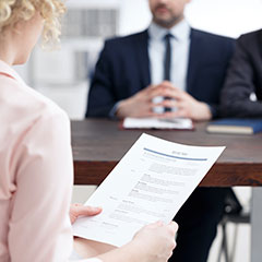 Woman holding resume in front of prospective employers